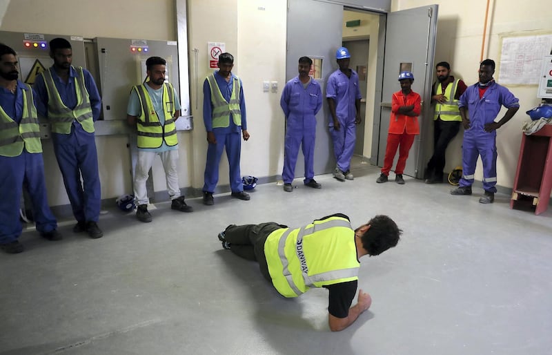 DUBAI ,  UNITED ARAB EMIRATES , JULY 3 – 2019 :- Hannes Loubser , fitness instructor with Iconic giving tips about the exercise to the DEWA construction workers during the fitness training session at the DEWA Sub Station near the International City in Dubai. ( Pawan Singh / The National ) For Lifestyle . Story by Melanie Swan