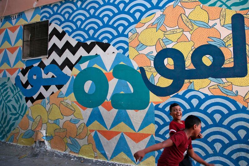Children walk past a mural paintingl. AFP