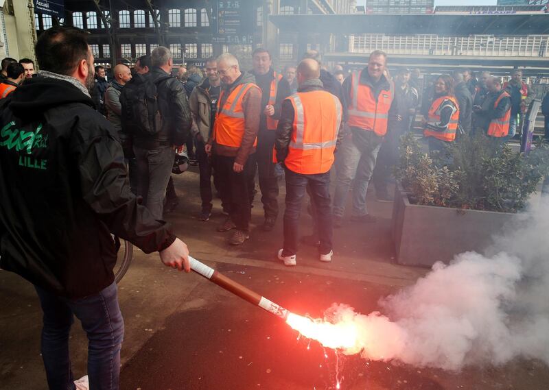 An employee of French state-owned railway company SNCF holds a safety flare during a gathering on a plateform at the Gare Lille Flandres railway station as part of a nationwide strike by French SNCF railway workers, France, April 3, 2018.  REUTERS/Pascal Rossignol