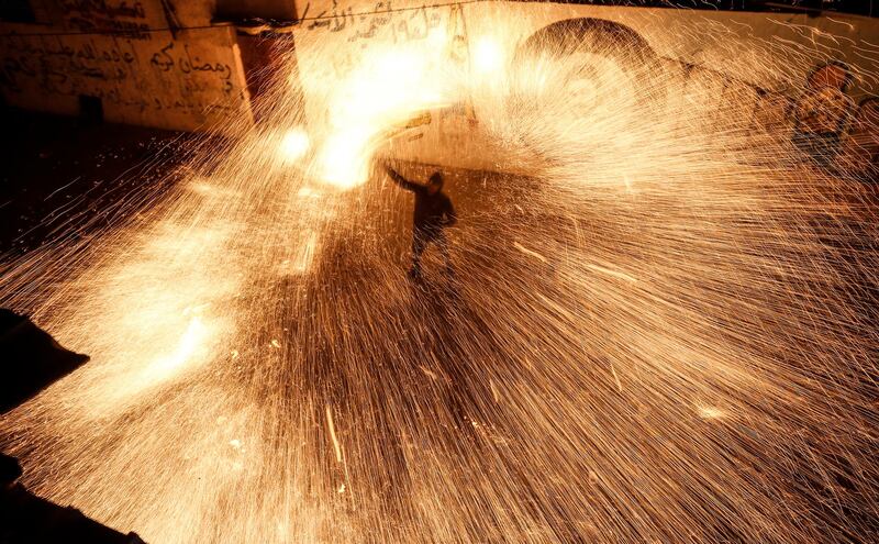 A Palestinian youth swings a homemade sparkler firework as people celebrate on a night of the Muslim holy month of Ramadan in Rafah refugee camp, in the southern Gaza Strip, on May 4, 2020. (Photo by MAHMUD HAMS / AFP)