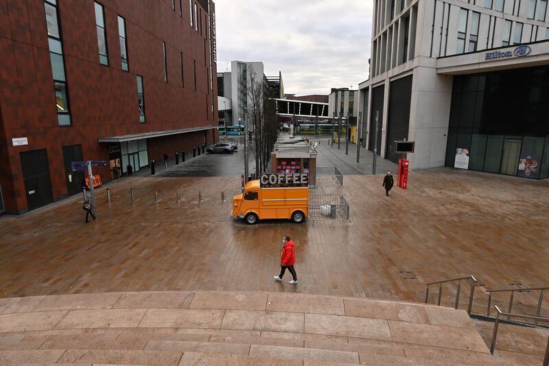 A pedestrian walks past a closed down Coffee-shop on an almost deserted street in Liverpool. AFP