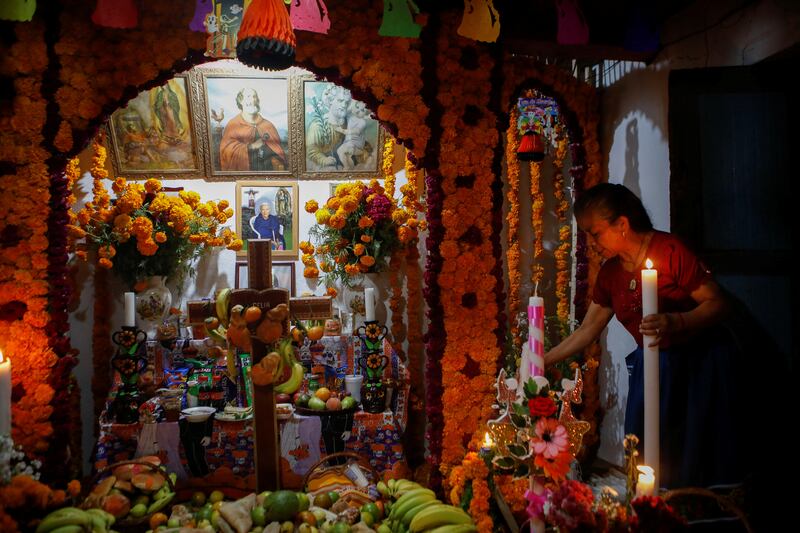 A woman places a candle at an altar for her mother who died recently during the annual Day of the Dead celebration in Mexico on November 1. Reuters