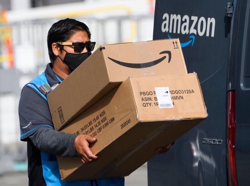 (FILES) In this file photo taken on February 02, 2021, an Amazon delivery driver carries boxes into a van outside of a distribution facility in Hawthorne, California. A week of blockbuster earnings reports from Big Tech culminates Thursday with Amazon revealing profits from pandemic-revved online shopping and growing reliance on internet-hosted services. The e-commerce colossus is among the internet giants whose businesses thrived as precautions against Covid-19 led people around the world to go online for work, school, shopping and socializing. / AFP / Patrick T. FALLON
