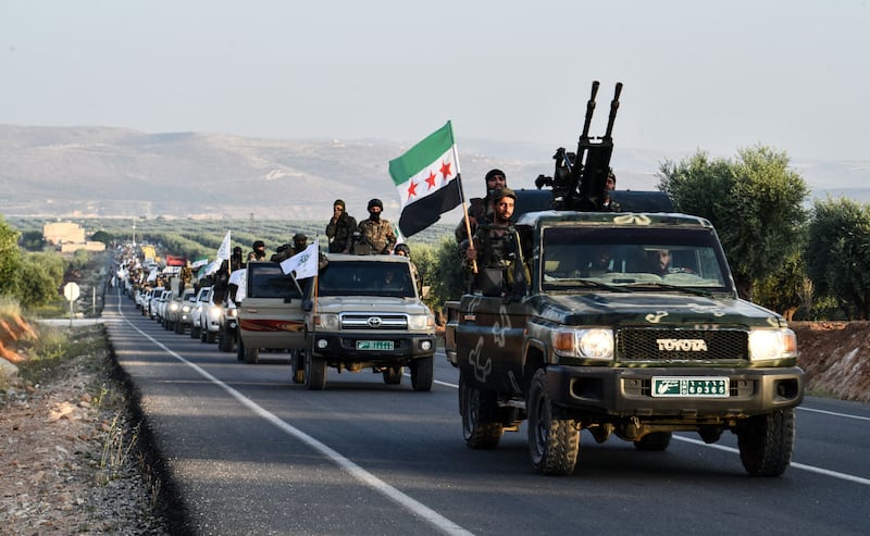 Turkey-backed Syrian fighters parade with their weapons in the countryside of the northwestern city of Afrin, in rebel-held part of Aleppo province, on June 1, 2022.  - Turkey's President Recep Tayyip Erdogan renewed threats of a military offensive in northern Syria, which he said would target Kurdish "terrorists".  (Photo by Rami al SAYED  /  AFP)