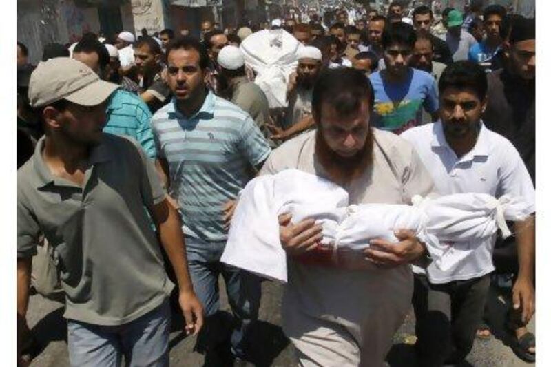 A Palestinian mourner carries the body of two-year-old Malek Shaat, who they say was killed in an Israeli air raid in August. Hatem Moussa / AP Photo