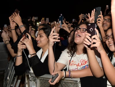 In this Thursday, July 18, 2019, photo, fans film and wave during the concert of Jeddah World Fest, at the King Abdullah Sports Stadium, in Jeddah, Saudi Arabia. Janet Jackson, Chris Brown, 50 Cent, Future and Tyga have been added to the lineup for the concert in Saudi Arabia that Nicki Minaj pulled out of because of human rights concerns. (AP Photo/Khalid Alhaj)