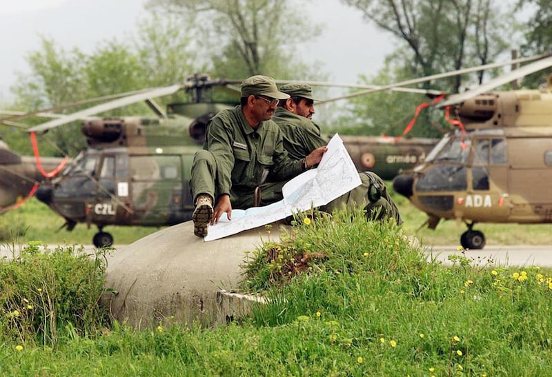 Soldiers from the United Arab Emirates sit atop a pillbox reading a map at the NATO humanitarian base at the Tirana Airport  28 April, 1999 in Albania.  The UAE Air Force flies 4 helicopter-missions a day to bring aid to Kosovar refugees in northern Albania.   (ELECTRONIC IMAGE)   AFP PHOTO    Mike NELSON/mn (Photo by MIKE NELSON / AFP)