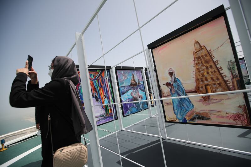 A visitor takes a selfie with artworks depicting 30 world heritage sites on display at the helipad of the Burj Al Arab Jumeirah in Dubai. EPA 