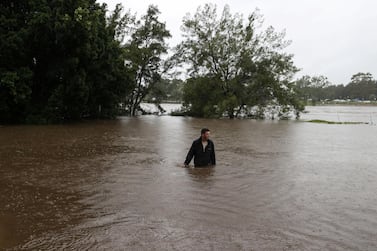 A man wades through floodwaters on a residential street in Sydney on March 21, 2021 as the Australian state of New South Wales experiences torrential rain. Reuters