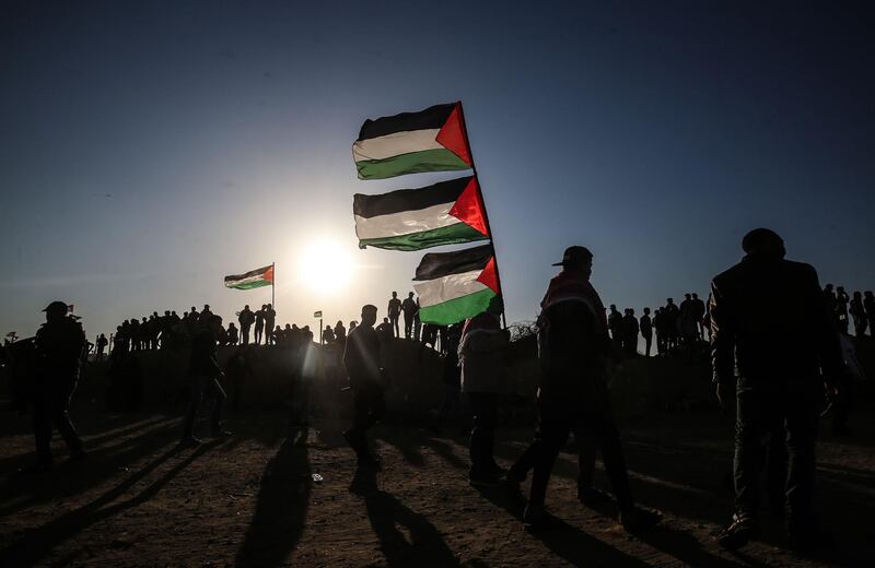Palestinian protesters carry their national flag during a demonstration near the border with Israel, east of Khan Yunis in the southern Gaza Strip, on April 12, 2019. A Palestinian teenager was shot dead by the Israeli army Friday during renewed clashes on the Gaza border, the health ministry in the Palestinian enclave said. A ministry spokesman said Maysara Abu Shaloof, 15, was "shot in the stomach by the (Israeli) occupation east of Jabalia," referring to a demonstration site in northern Gaza. / AFP / SAID KHATIB
