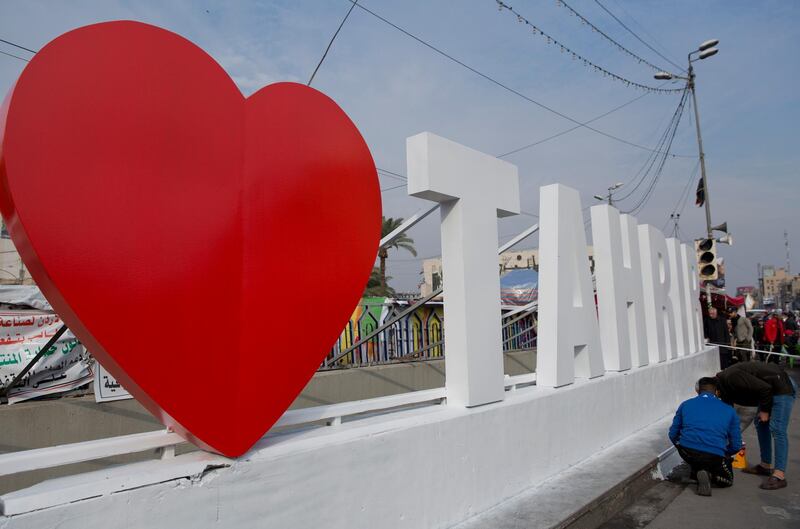 Activists put the last touches on a big sign at the Tahrir square, in Baghdad, Iraq, Tuesday, Dec. 10, 2019. Thousands of Iraqi protesters in the Iraqi capital Baghdad on Tuesday celebrated the two-year anniversary of the defeat of Islamic State group amid protests and public anger. (AP Photo/Nasser Nasser)