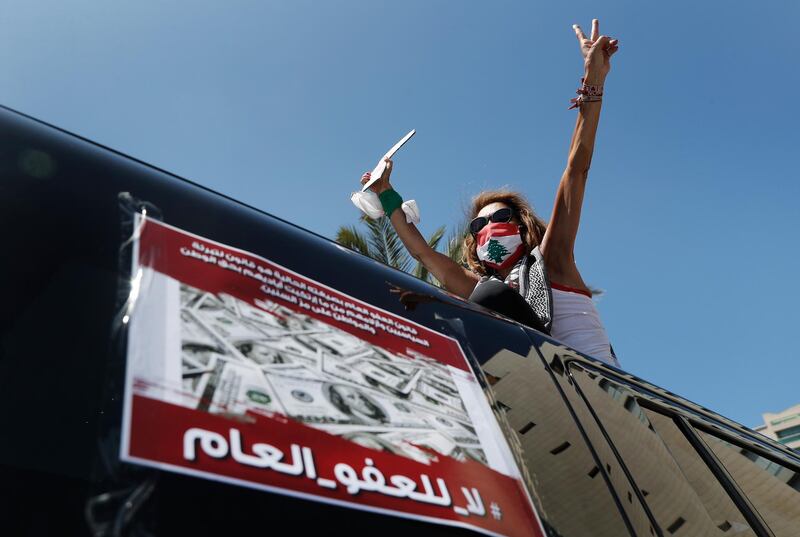 An anti-government protester stands on top of her car as she shouts slogans against a proposed parliament vote on a general amnesty law, in Beirut, Lebanon. The Arabic poster reads, "No to the general amnesty." AP Photo