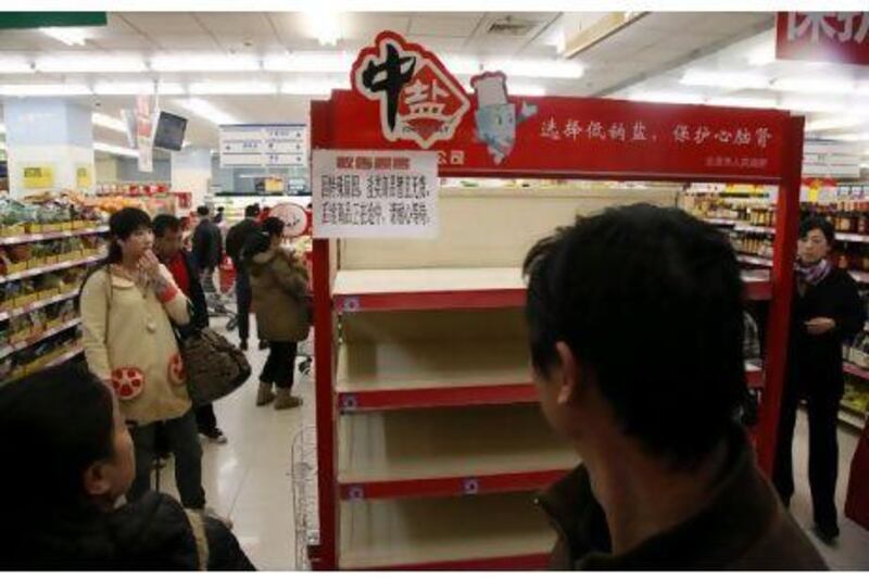 Shoppers look at empty shelves at a supermarket in Beijing, after worried shoppers stripped stores of salt cross China on Thursday in the false belief it can guard against radiation exposure.