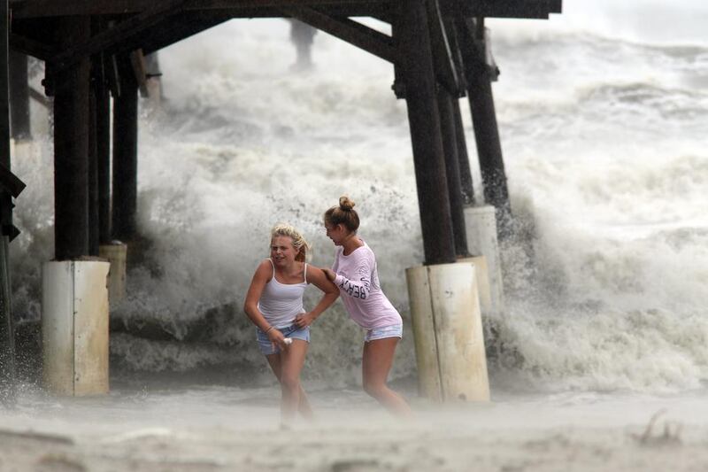 Kaleigh Black, left, and Amber Olsen run for cover as a squall with rain and wind from the remnants of Hurricane Matthew pelt them as they explore the Cocoa Beach Pier in Florida. Douglas R Clifford / Tampa Bay Times via AP