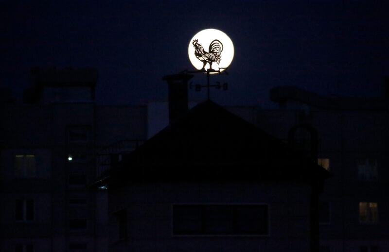 The full Moon rises behind a rooster figure above apartments in Minsk, Belarus. EPA