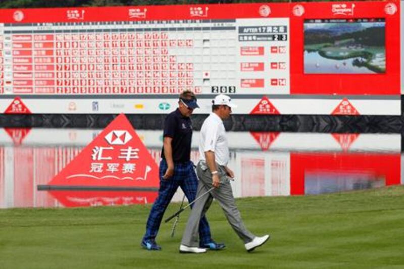 Lee Westwood and Ian Poulter walk past the scoreboard during day three of the WGC Champions Tournament in Dongguan