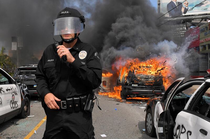 Los Angeles Police Department commander Cory Palka stands among several destroyed police cars as one explodes during a protest in Los Angeles. AP Photo