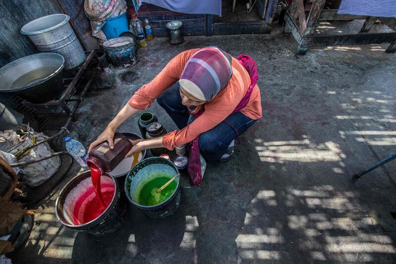 The Egyptian batik designer pours paint into a bucket at her workshop in Old Cairo.