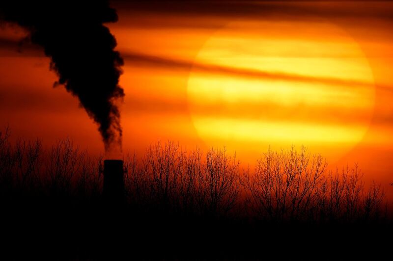 FILE - In this Feb. 1, 2021 file photo, emissions from a coal-fired power plant are silhouetted against the setting sun in Independence, Mo. President Joe Biden faces a vexing task as he convenes a virtual climate summit on Thursday. He is expected to present a nonbinding but symbolic goal to reduce greenhouse gas emissions that will have a tangible impact not only on climate change efforts in the U.S. but throughout the world. (AP Photo/Charlie Riedel, File)
