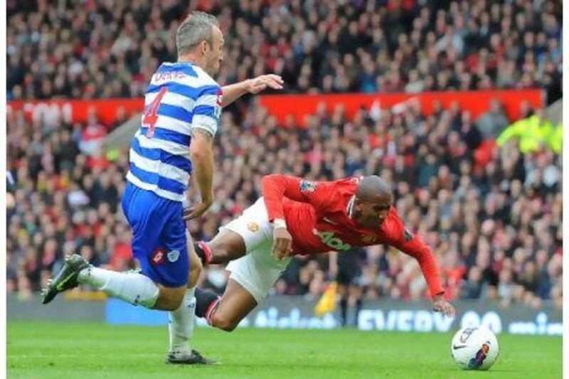Manchester United's Ashley Young falls under the challenge of QPRs Shaun Derry to win a penalty.