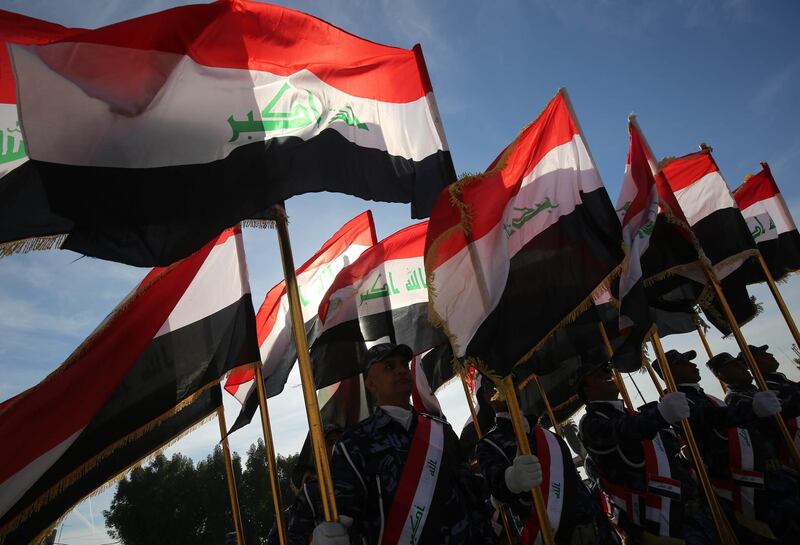 Iraqi policemen hold their national flag and march during a parade in Baghdad. AFP