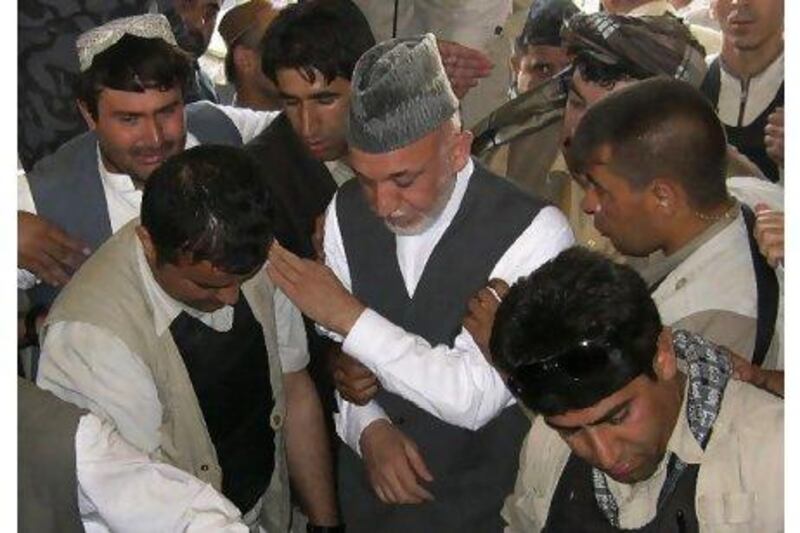 President Hamid Karzai, centre, attends the burial of his half brother Ahmed Wali Karzai in his family's ancestral village of Karz, in Kandahar province, Afghanistan, yesterday. AP Photo