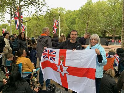 Gale Tate and her daughter’s boyfriend Andrew Hoey hold up the Northern Irish flag as they await the arrival of the queen's coffin on The Mall. The National