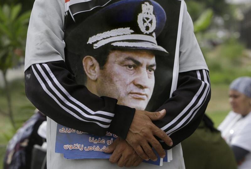 A supporter of ousted Egyptian President Hosni Mubarak hugs his poster in front of the Maadi Military Hospital, in Cairo. Amr Nabil / AP Photo