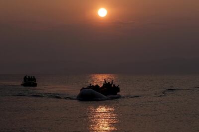 FILE PHOTO: Refugees and migrants wave as they approach the shores of the Greek island of Lesbos on a dinghy during sunrise, March 20, 2016. REUTERS/Alkis Konstantinidis/File Photo