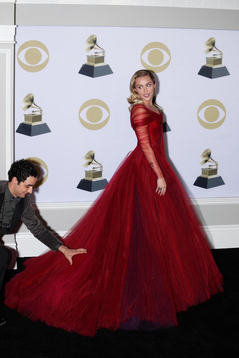 epa06483169 Zac Posen (L) adjusts Miley Cyrus' dress as she poses in the press roomduring the 60th annual Grammy Awards ceremony at Madison Square Garden in New York, New York, USA, 28 January 2018.  EPA-EFE/JUSTIN LANE