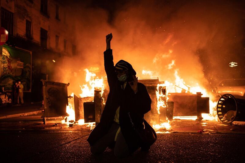 A demonstrator raises their fist as a fire burns in the street after clashes with law enforcement near the Seattle Police Departments East Precinct. Getty Images via AFP