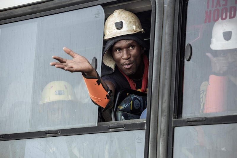 A rescued miner gestures out a bus window carrying some of the hundreds of miners rescued from the Beatrix gold mine shaft. Gianluigi Guercia / AFP