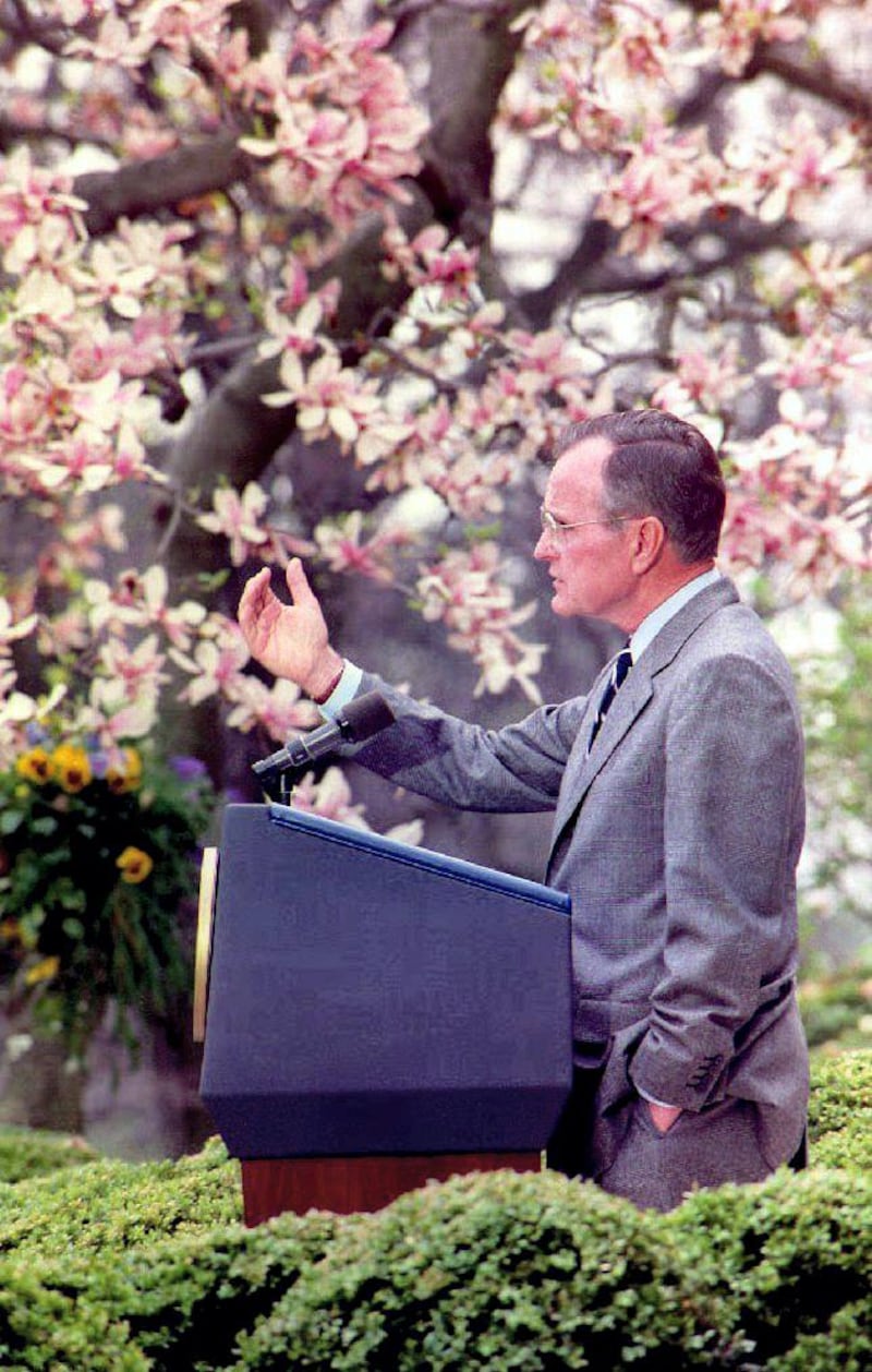 U.S. President George Bush gestures toward reporters during an outdoor press conference in the White House Rose Garden 10 April, 1992. Standing next to a magnolia tree in full bloom, President Bush said he has ordered his campaign workers to "stay out of the sleaze business".  AFP (Photo by J. DAVID AKE / AFP)