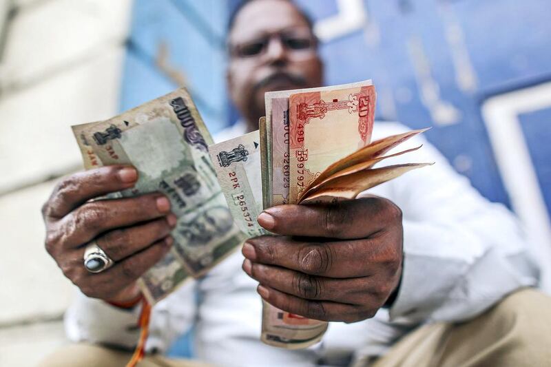 The Indian rupee could weaken towards 63 against the dollar followed by a further slide to 65 in the coming weeks, one forecast noted. Dhiraj Singh / Bloomberg News