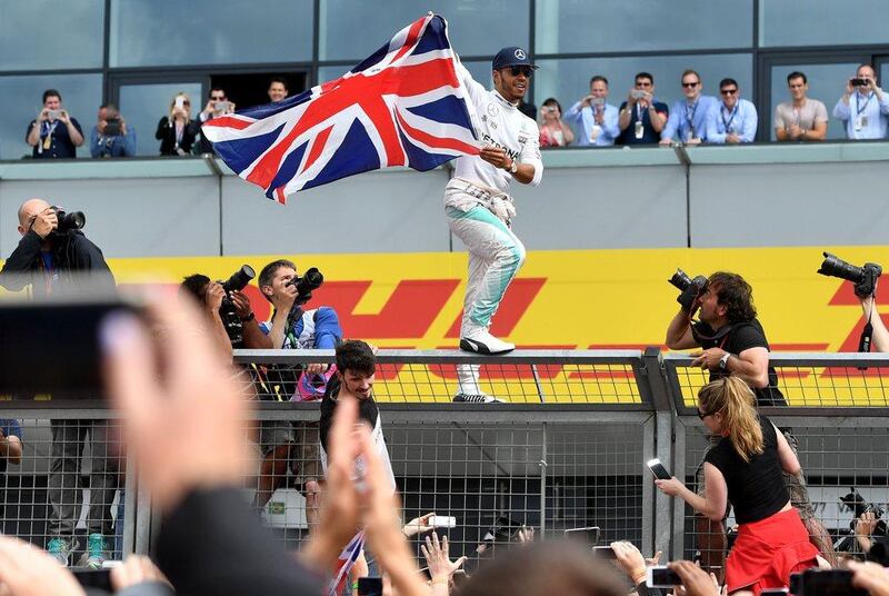 Lewis Hamilton celebrates with fans after climbing the paddock fence after winning the British Formula One Grand Prix at Silverstone. Andrej Isakovic / AFP