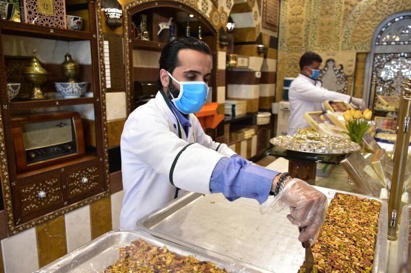A vendor wearing face mask sells sweets at al-Midan neighborhood ahead of the month of Ramadan in Damascus, Syria.  EPA