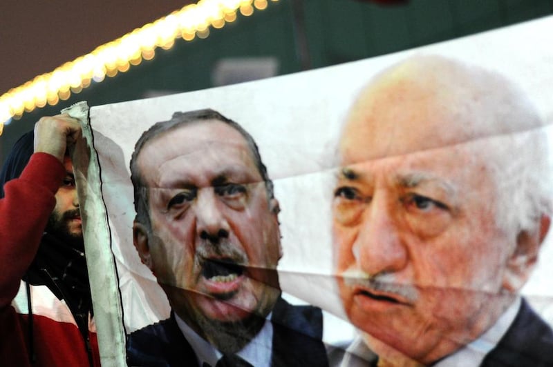 A Turkish protester in Istanbul holds up a banner with pictures of Turkish prime minister Recep Tayyip Erdogan and US-based Turkish cleric Fethullah Gulen during a demonstration against the goverment on December 30, 2013. Ozan Kose/AFP Photo
