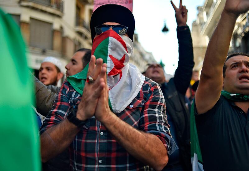 An Algerian demonstrator, his face covered with a national flag,  takes part in an anti-government protest in the capital Algiers. AFP