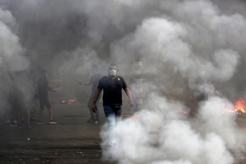 An anti-government protester walks between burning tyres in Beirut, Lebanon. AP Photo