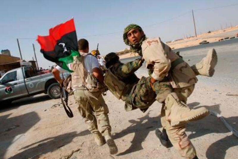 Anti-Gaddafi fighters carry their wounded comrade during fighting at the frontline, in the north of the besieged city of Bani Walid September 16, 2011. The forces of Libya's new leaders attacked two besieged towns on Friday, storming into Bani Walid and pushing forward at Sirte, as they tried to finish off resistance from diehard supporters of Muammar Gaddafi. REUTERS/Youssef Boudlal (LIBYA - Tags: CIVIL UNREST CONFLICT MILITARY) *** Local Caption ***  YB233_LIBYA_0916_11.JPG