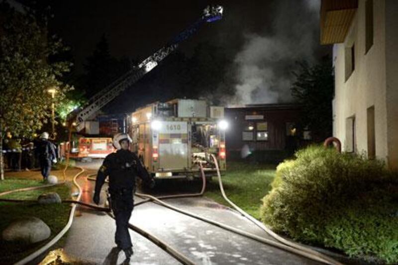 Swedish fire crews and police secure an area where a fire was started by rioters in a Stockholm suburb.