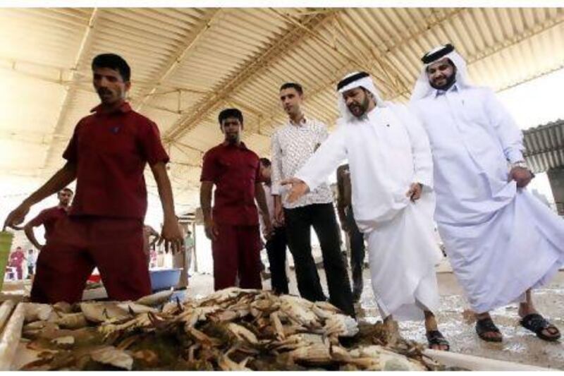 Dr Hashim Al Nuaimi, left, the Ministry of Economy's head of consumer protection, and Ibrahim Rashed, an economic inspector, check the condition and price of produce at the fish market in Umm Al Qaiwain.