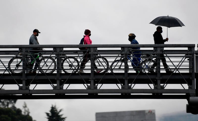 People take their bicycles across a pedestrian bridge in Bogota. AFP