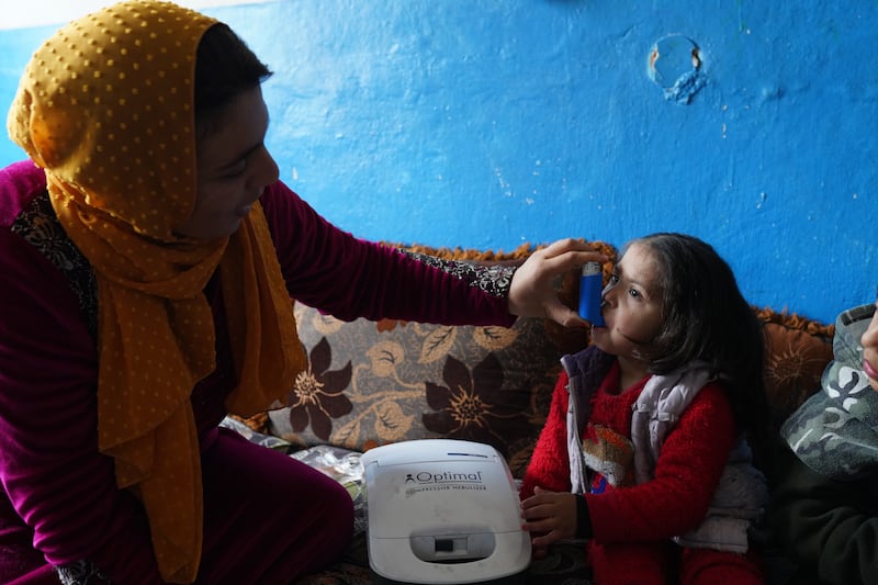Aisha Mohammed Ali, 25, a mother of five who is a refugee from Aleppo, Syria, assists one of her daughters, who has asthma.