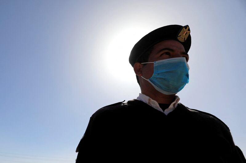 A police officer wearing a protective mask against Covid-19 stands near Colossi of Memnon in the West Bank of Luxor, Egypt. Reuters