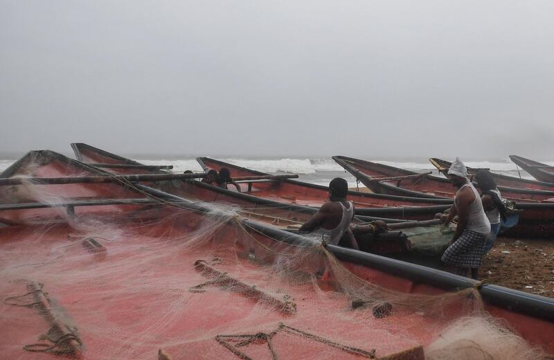 Indian fishermen pull a boat to higher ground. AFP
