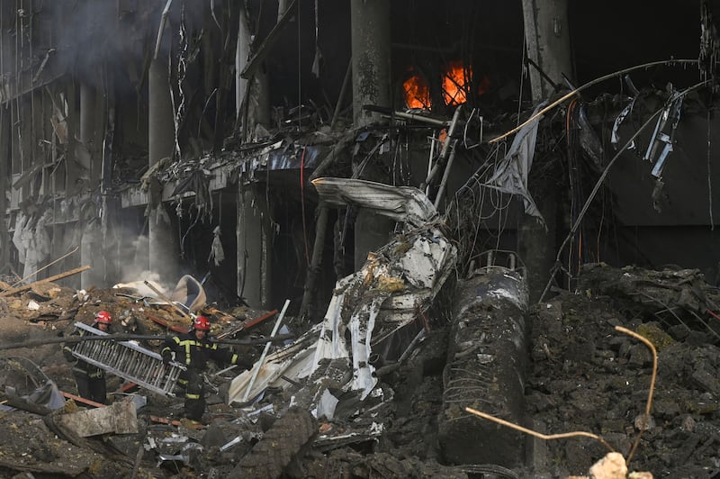 Firefighters carry a ladder across the debris following Russian shellings that destroyed the Retroville shopping mall in Kyiv. AFP