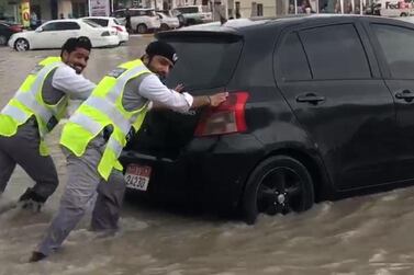 Two soaking wet police officers laugh as they help a driver through a pocket of water near Ras Al Khaimah city on Saturday, January 11 2020. Courtesy: RAK Police