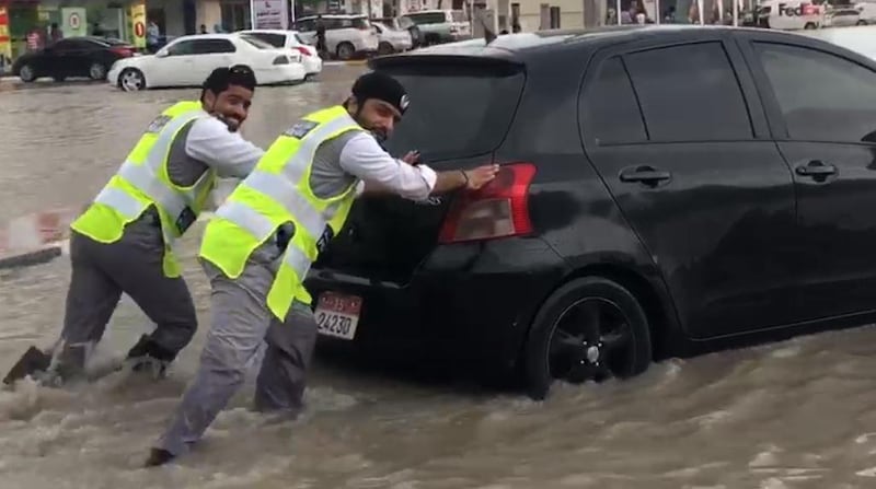 Two soaking wet police officers laugh as they help a driver through a pocket of water near Ras Al Khaimah city on Saturday, January 11 2020. Courtesy: RAK Police