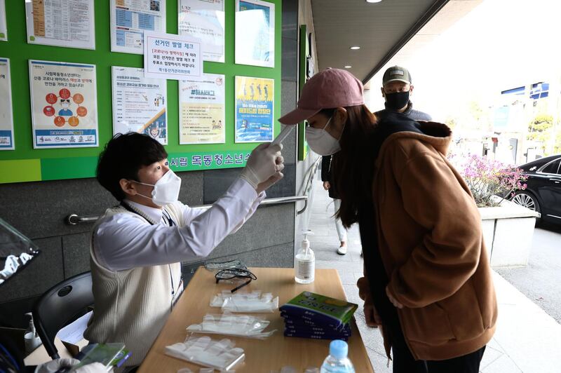 SEOUL, SOUTH KOREA - APRIL 15: A South Korean woman wears plastic gloves has her temperature checked upon his arrival to cast her vote for Parliamentary election amid the coronavirus outbreak on April 15, 2020 in Seoul, South Korea. Parliamentary voting started at local polling stations across South Korea prior to the election. A total of 300 lawmakers will be elected to the four-year term, with 253 of them to be selected through direct elections and the remaining 47 assigned via proportional representation. A total of 1,110 candidates are competing for the 253 seats. South Korea has called for expanded public participation in social distancing, as the country witnesses a wave of community spread and imported infections leading to a resurgence in new cases of COVID-19. According to the Korea Center for Disease Control and Prevention, 27 new cases were reported. The total number of infections in the nation tallies at 10,450. (Photo by Chung Sung-Jun/Getty Images)